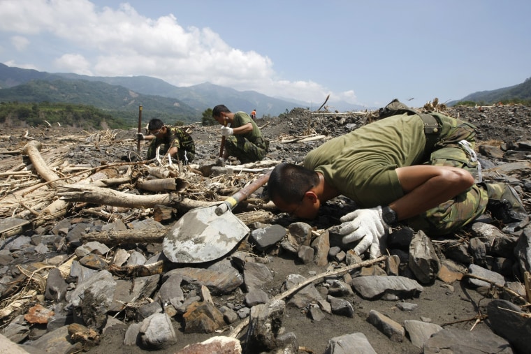 Image: A soldier smells the ground while looking for the bodies of flood victims in the mudslide-affected village of Sinkai, following Typhoon Morakot in Kaohsiung County